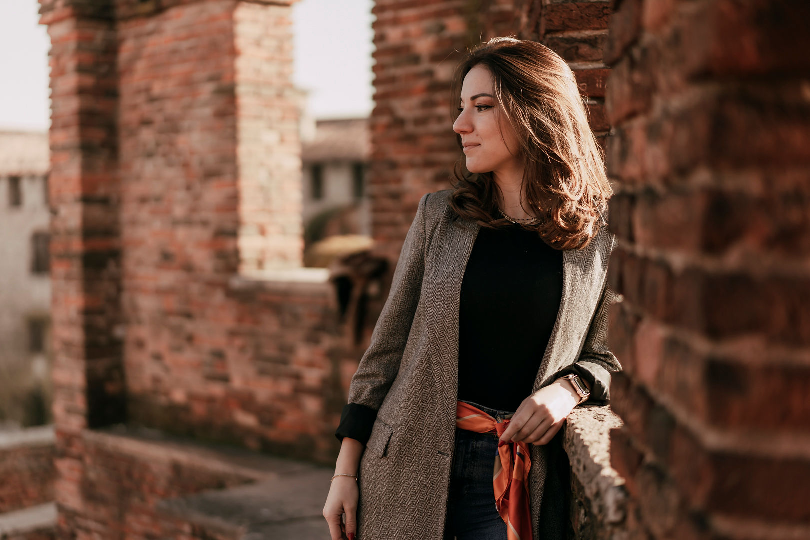 Francesca Zecchin standing against a warm brick wall, looking into the distance with quiet confidence